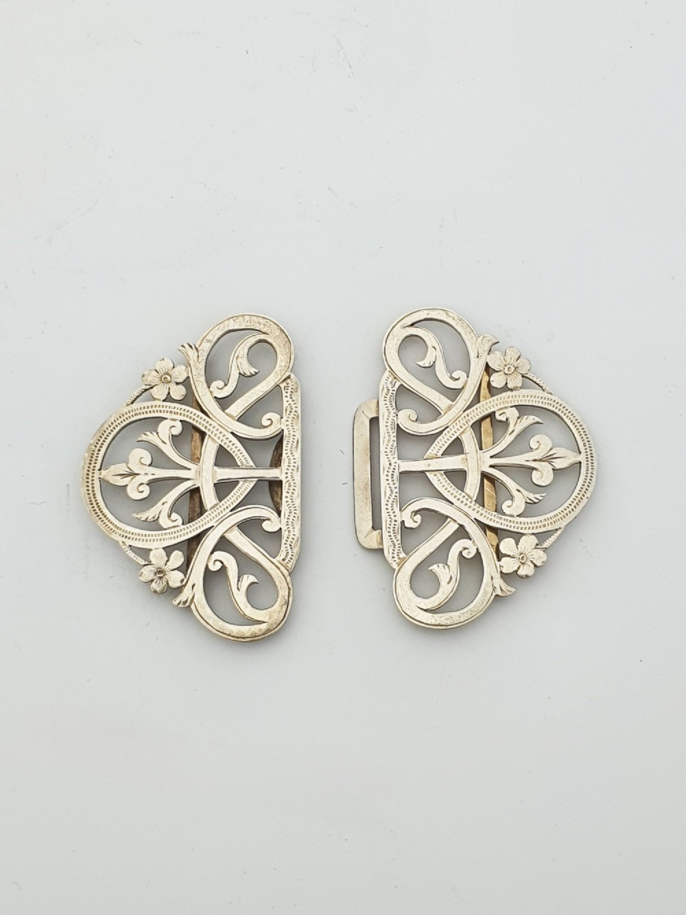 An Edwardian two-part sterling silver belt buckle featuring pierced scrollwork and floral motifs. View V