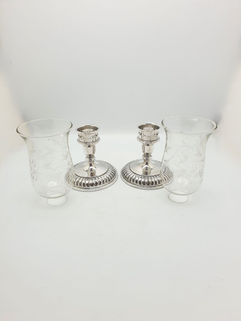 A pair of silver-plated candle holders featuring gadrooned bases and pierced sockets topped with etched glass hurricane shades. View VI