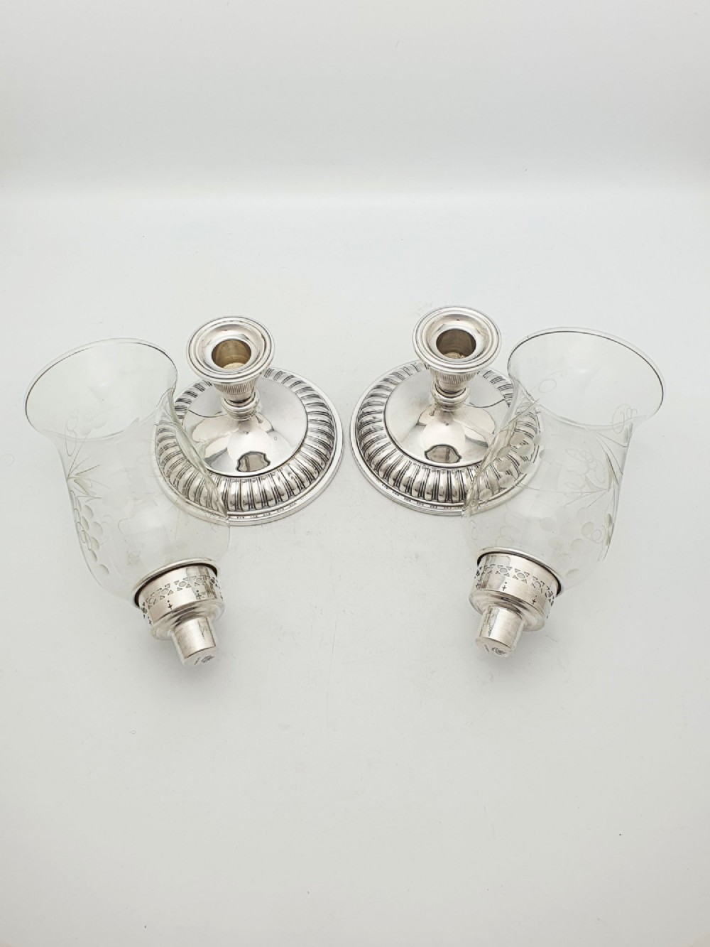 A pair of silver-plated candle holders featuring gadrooned bases and pierced sockets topped with etched glass hurricane shades. View VII