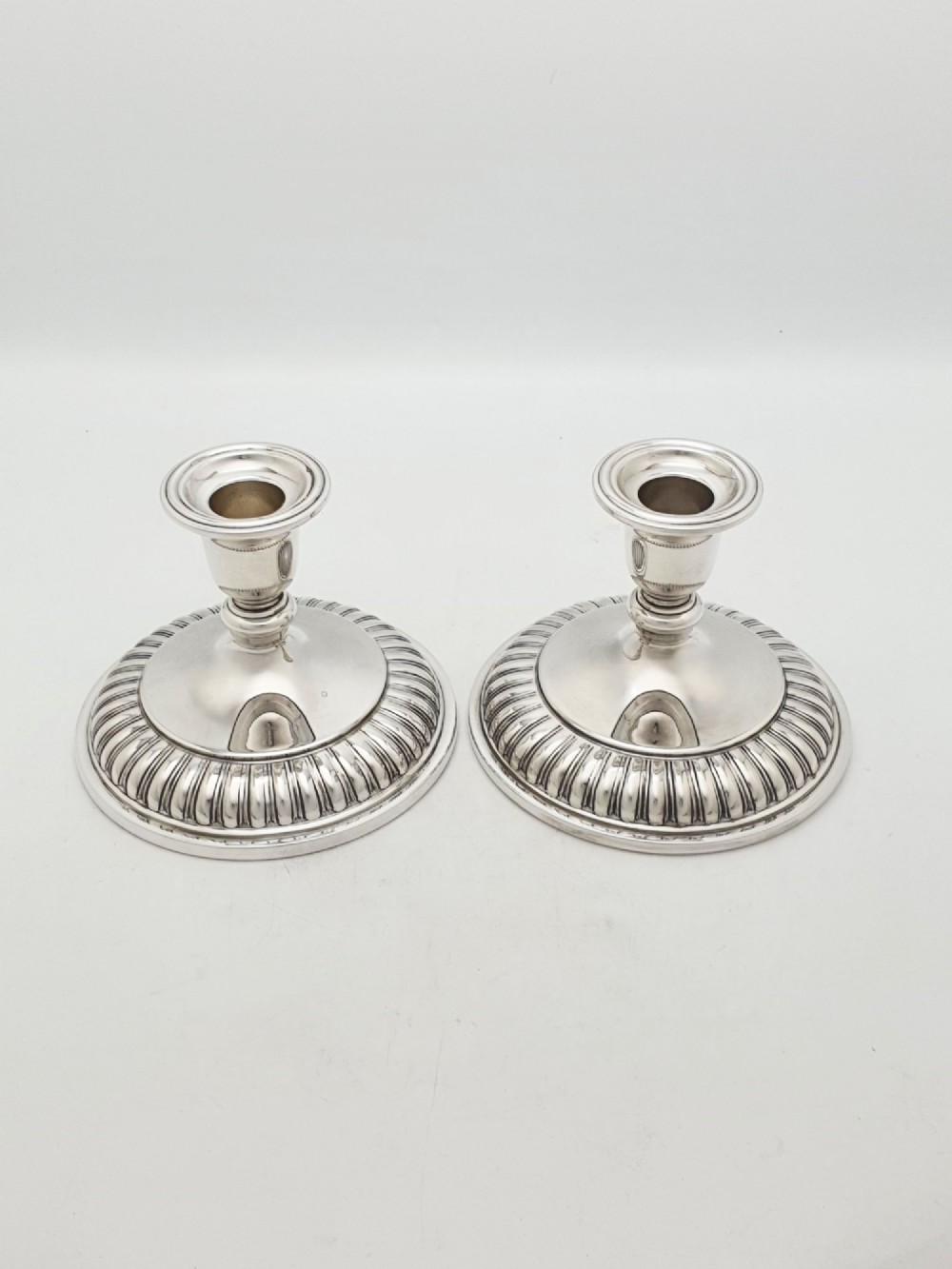 A pair of silver-plated candle holders featuring gadrooned bases and pierced sockets topped with etched glass hurricane shades. View IX