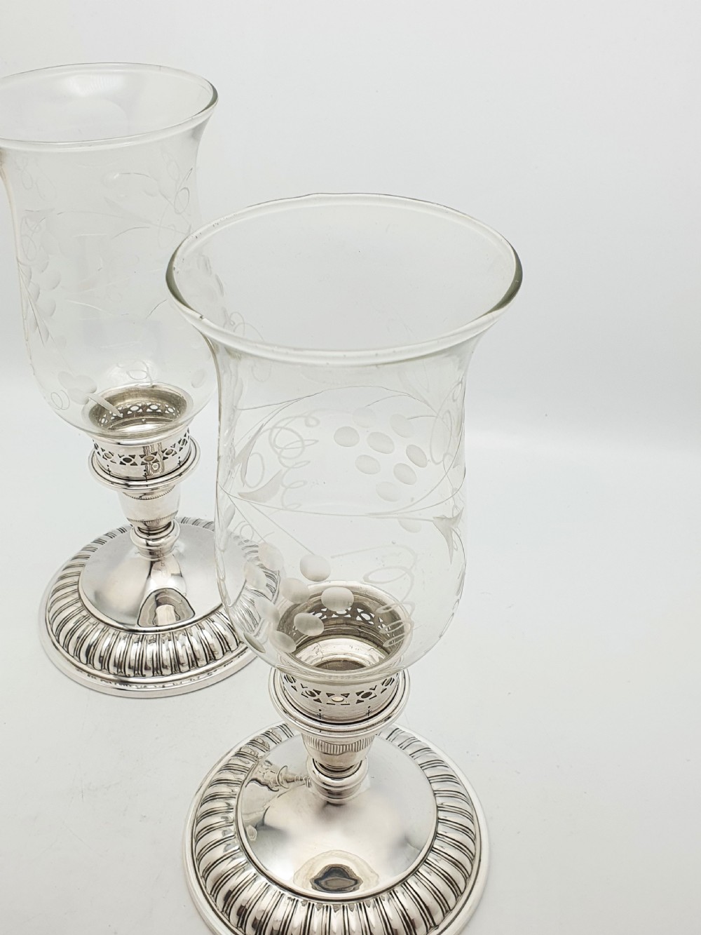 A pair of silver-plated candlestick bases fitted with clear etched glass hurricane shades featuring subtle floral patterns. View II