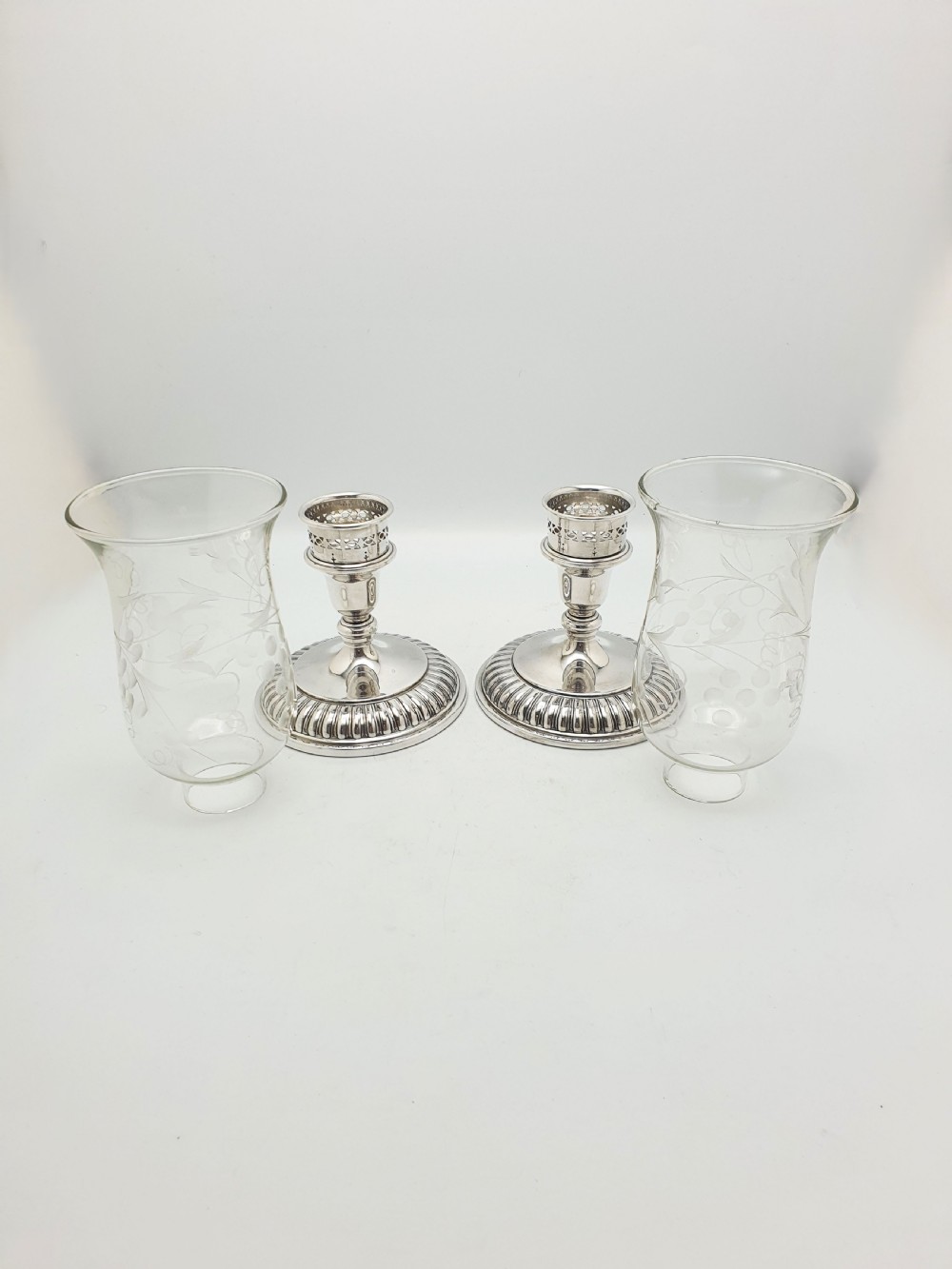 A pair of silver-plated candlestick bases fitted with clear etched glass hurricane shades featuring subtle floral patterns. View VI
