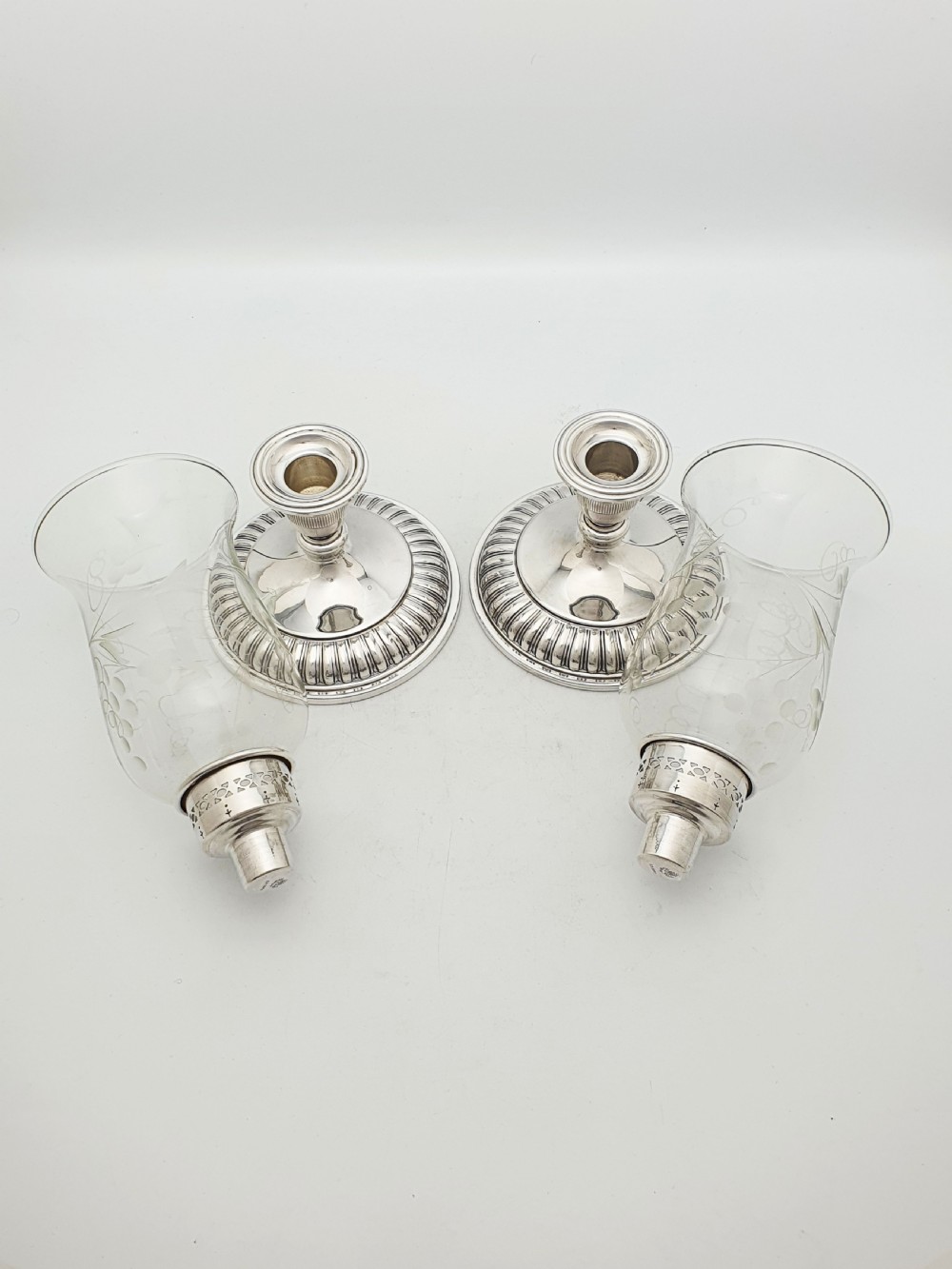 A pair of silver-plated candlestick bases fitted with clear etched glass hurricane shades featuring subtle floral patterns. View VII