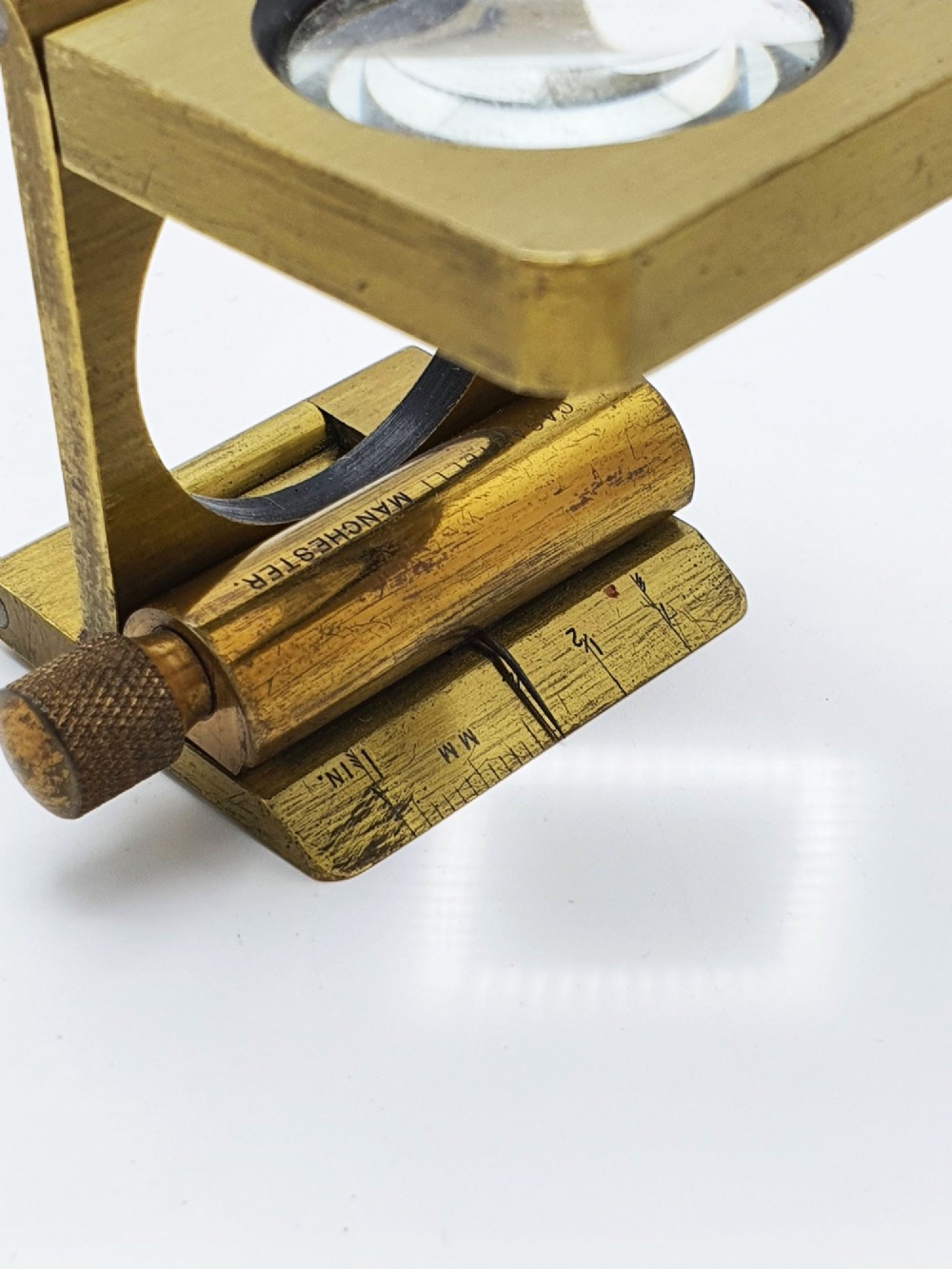 A vintage Edwardian folding brass linen tester loupe with a glass lens and measuring scale engraved on the base plate. View VIII