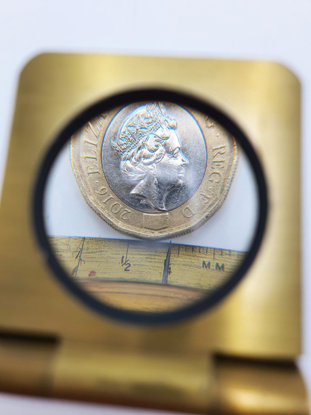 A vintage Edwardian folding brass linen tester loupe with a glass lens and measuring scale engraved on the base plate. View X