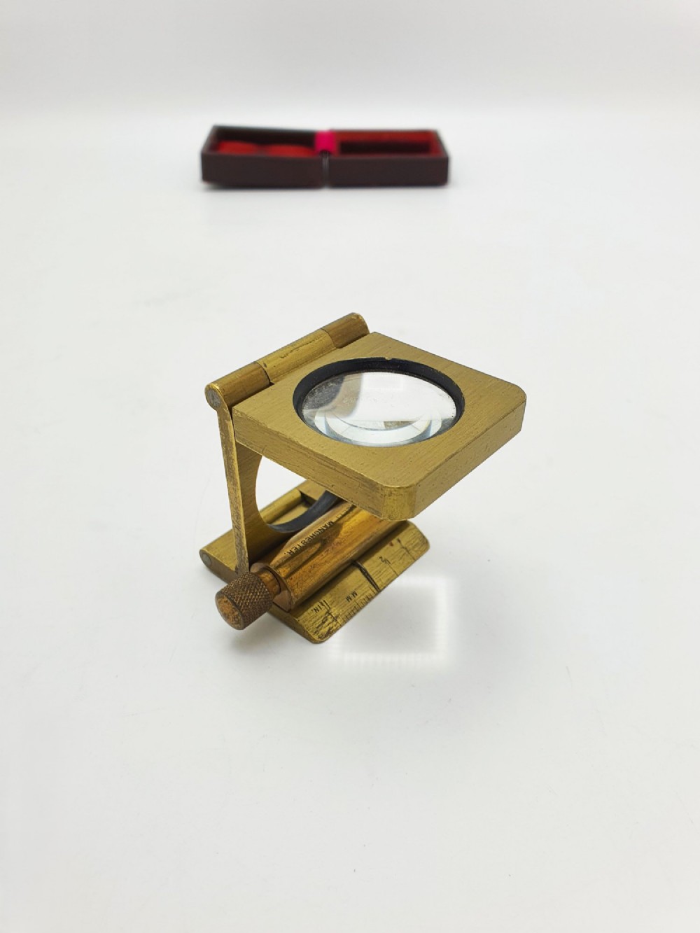 A vintage Edwardian folding brass linen tester loupe with a glass lens and measuring scale engraved on the base plate. View XI