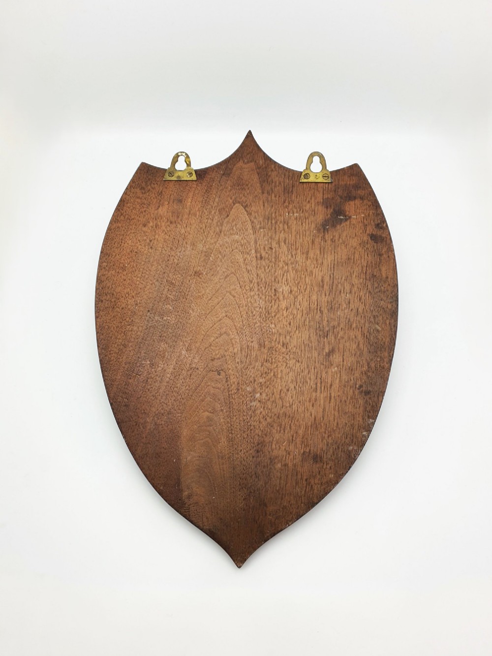 A shield-shaped mahogany wall plaque equipped with three decorative cast brass coat hooks arranged symmetrically. View VIII