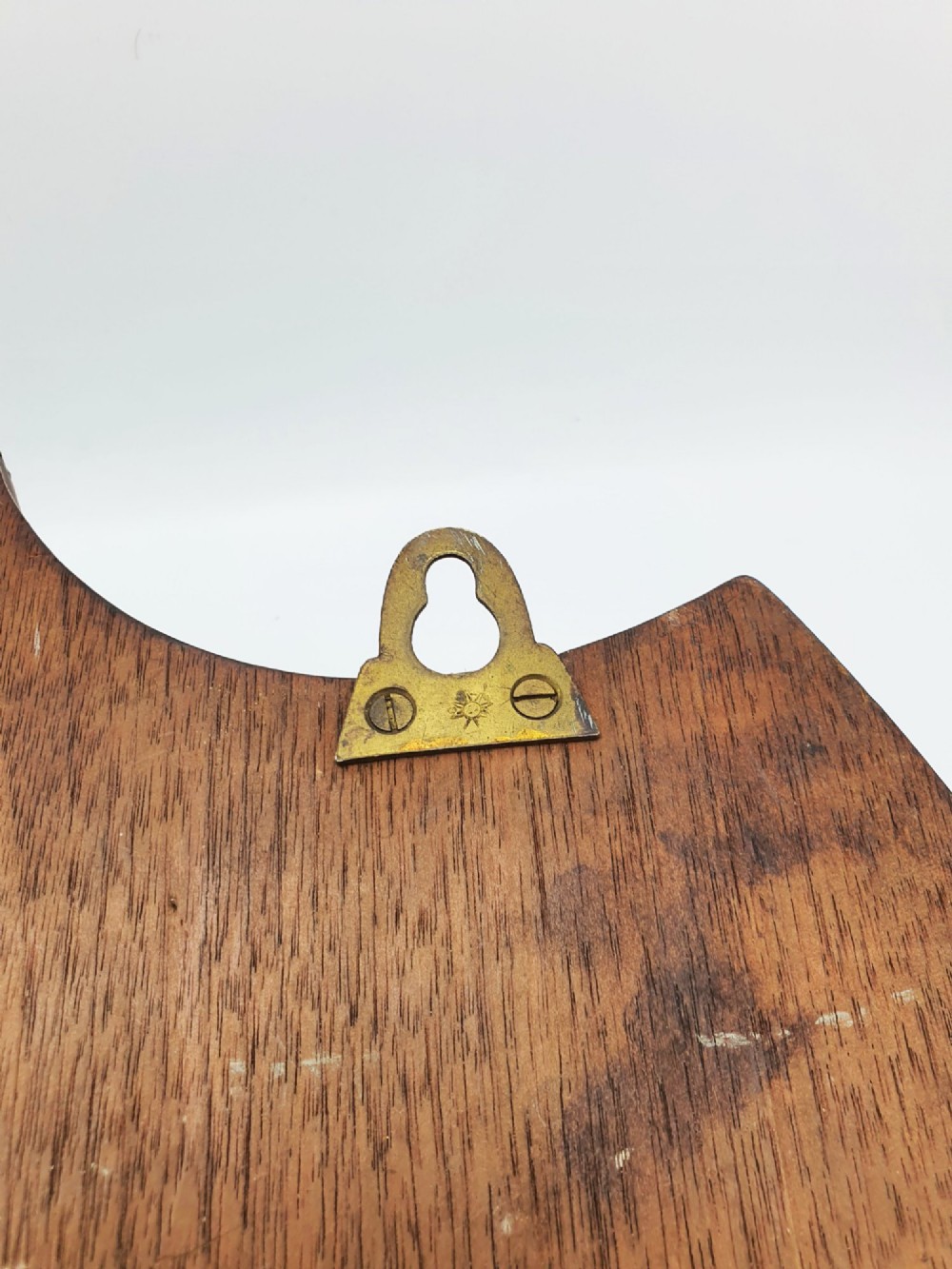 A shield-shaped mahogany wall plaque equipped with three decorative cast brass coat hooks arranged symmetrically. View IX