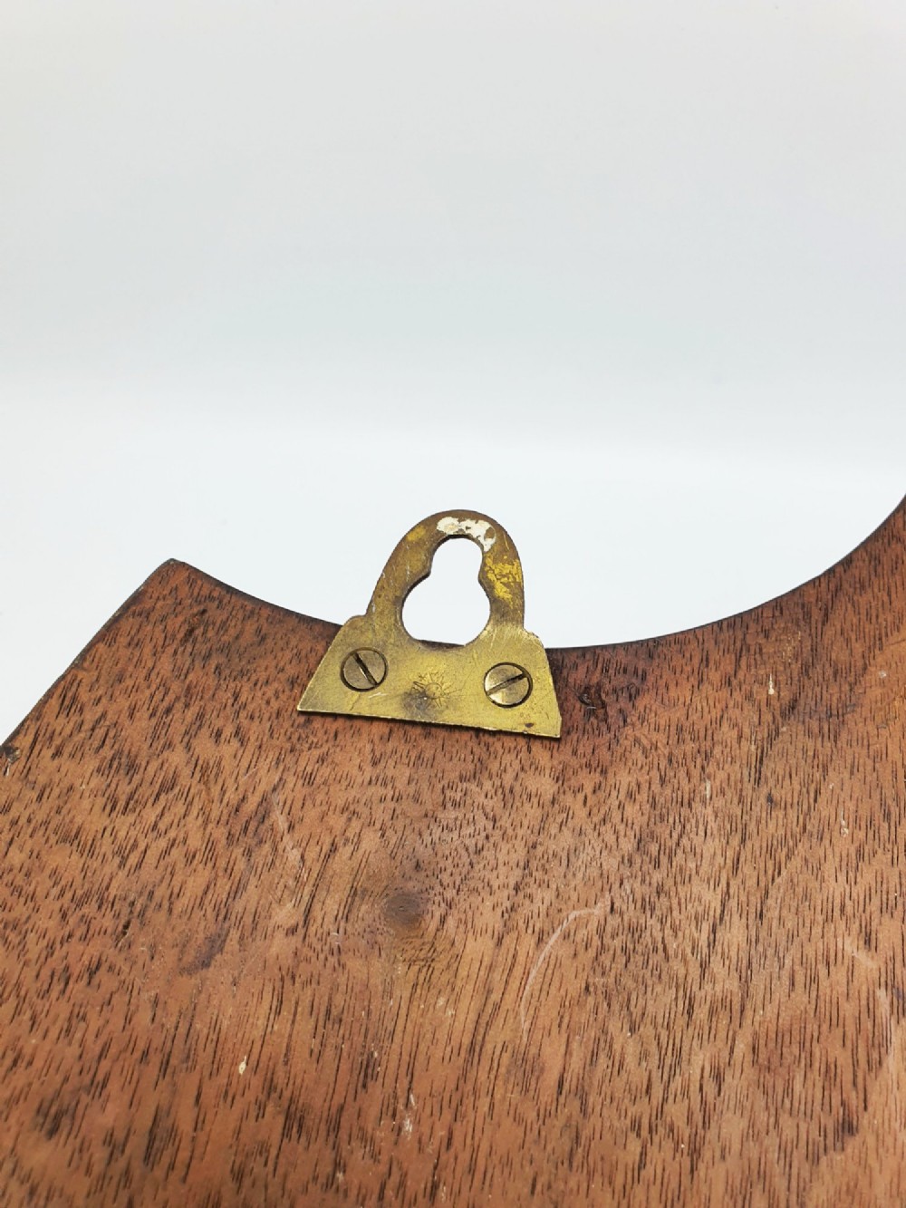 A shield-shaped mahogany wall plaque equipped with three decorative cast brass coat hooks arranged symmetrically. View X
