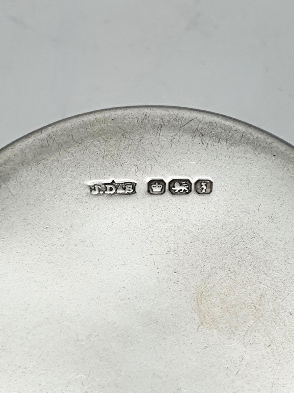 A circular sterling silver pill box featuring engine-turned linear engraving, small dots, and a central plain round cartouche. View IV