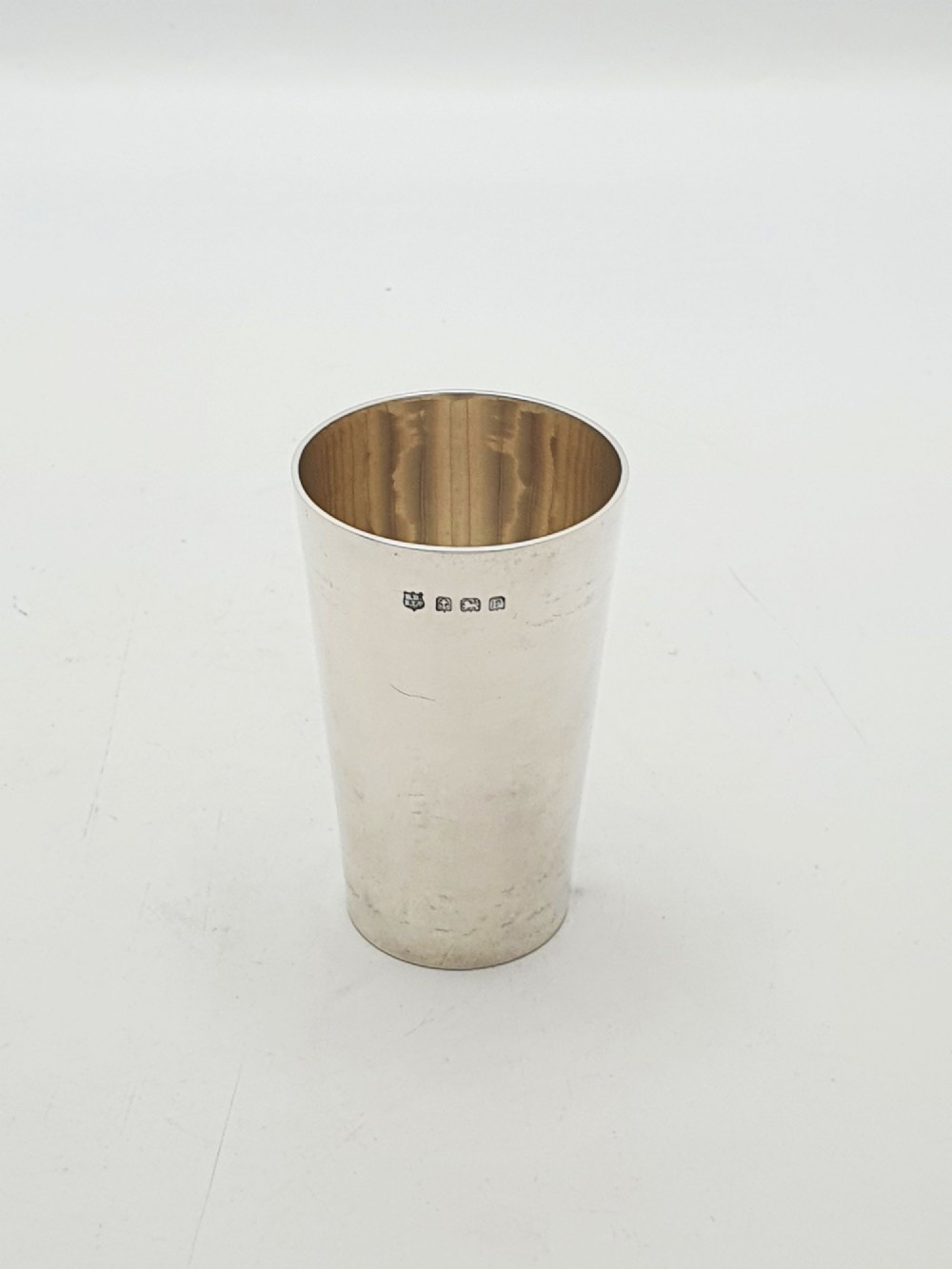 A polished Art Deco sterling silver travel beaker standing beside its fitted tan leather carrying case. View III