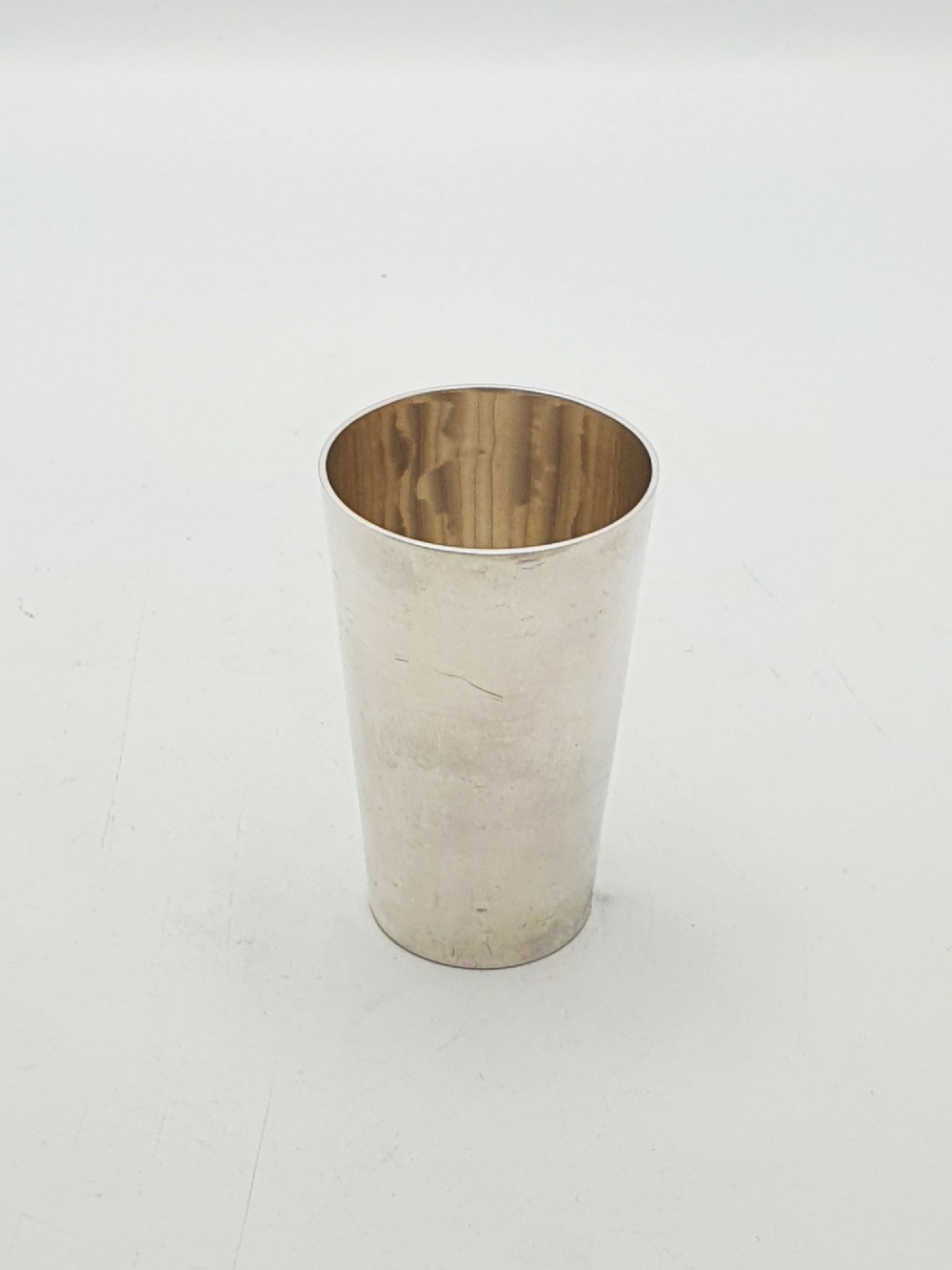 A polished Art Deco sterling silver travel beaker standing beside its fitted tan leather carrying case. View IV