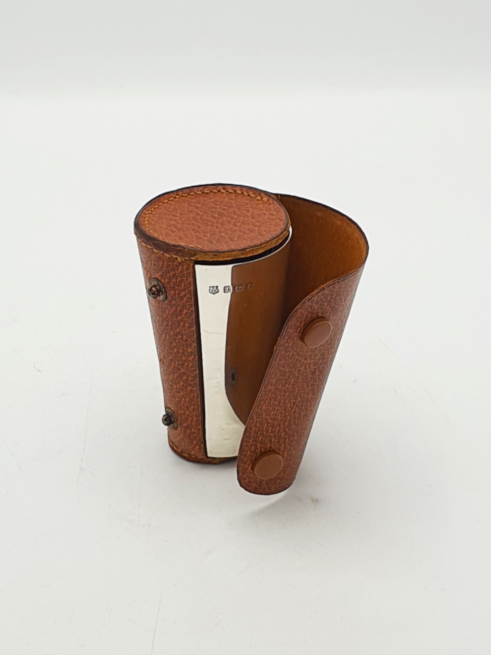 A polished Art Deco sterling silver travel beaker standing beside its fitted tan leather carrying case. View VI