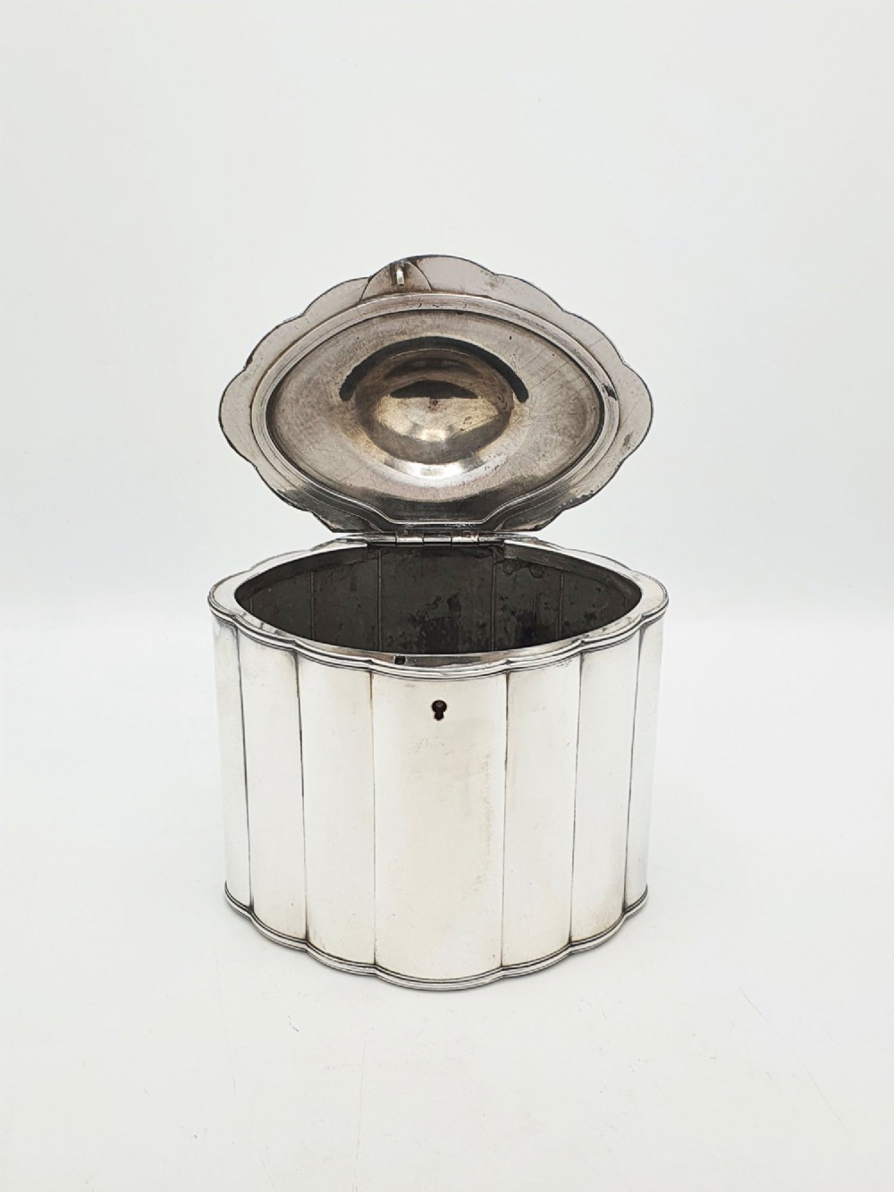 A lobed Georgian Sheffield plated tea caddy featuring vertical fluting, a central keyhole, and a domed lid topped with an urn finial. View II