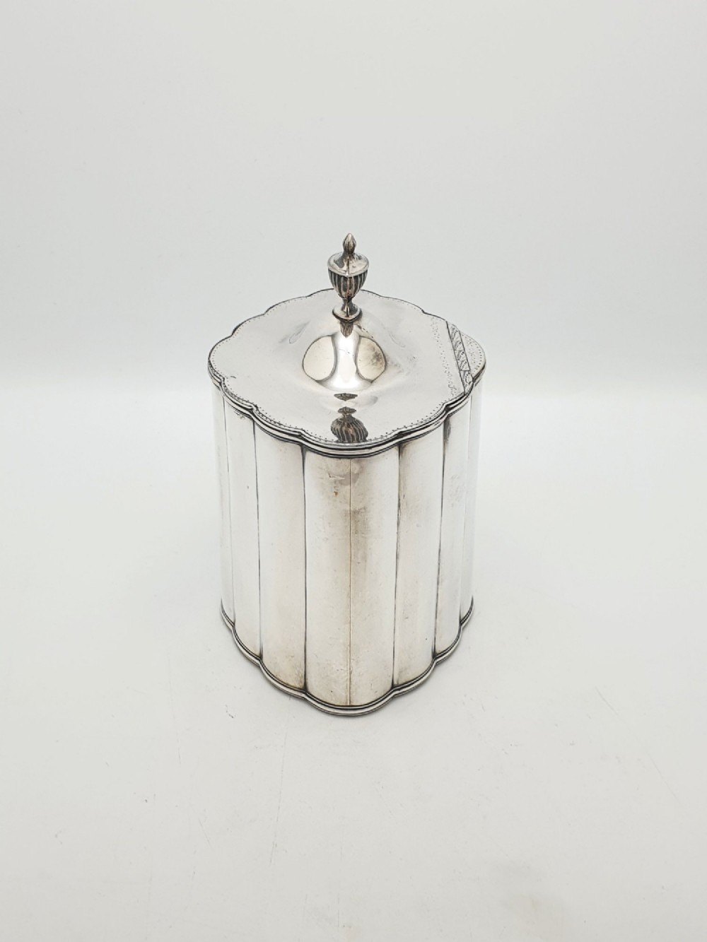 A lobed Georgian Sheffield plated tea caddy featuring vertical fluting, a central keyhole, and a domed lid topped with an urn finial. View IV
