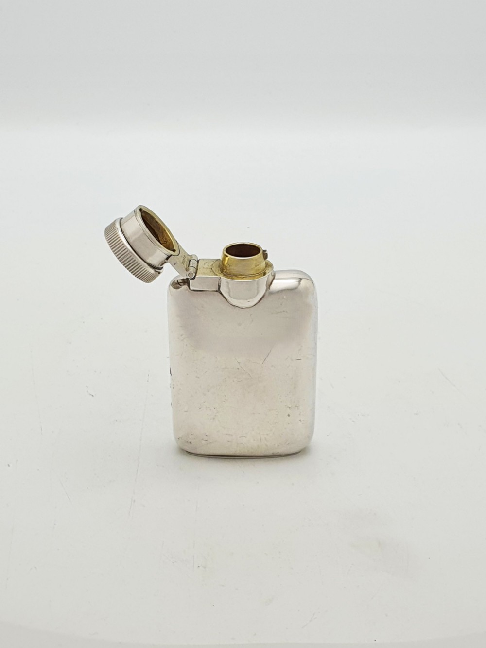 A small sterling silver rectangular hip flask with rounded corners and a hinged bayonet cap set against a plain white background. View II