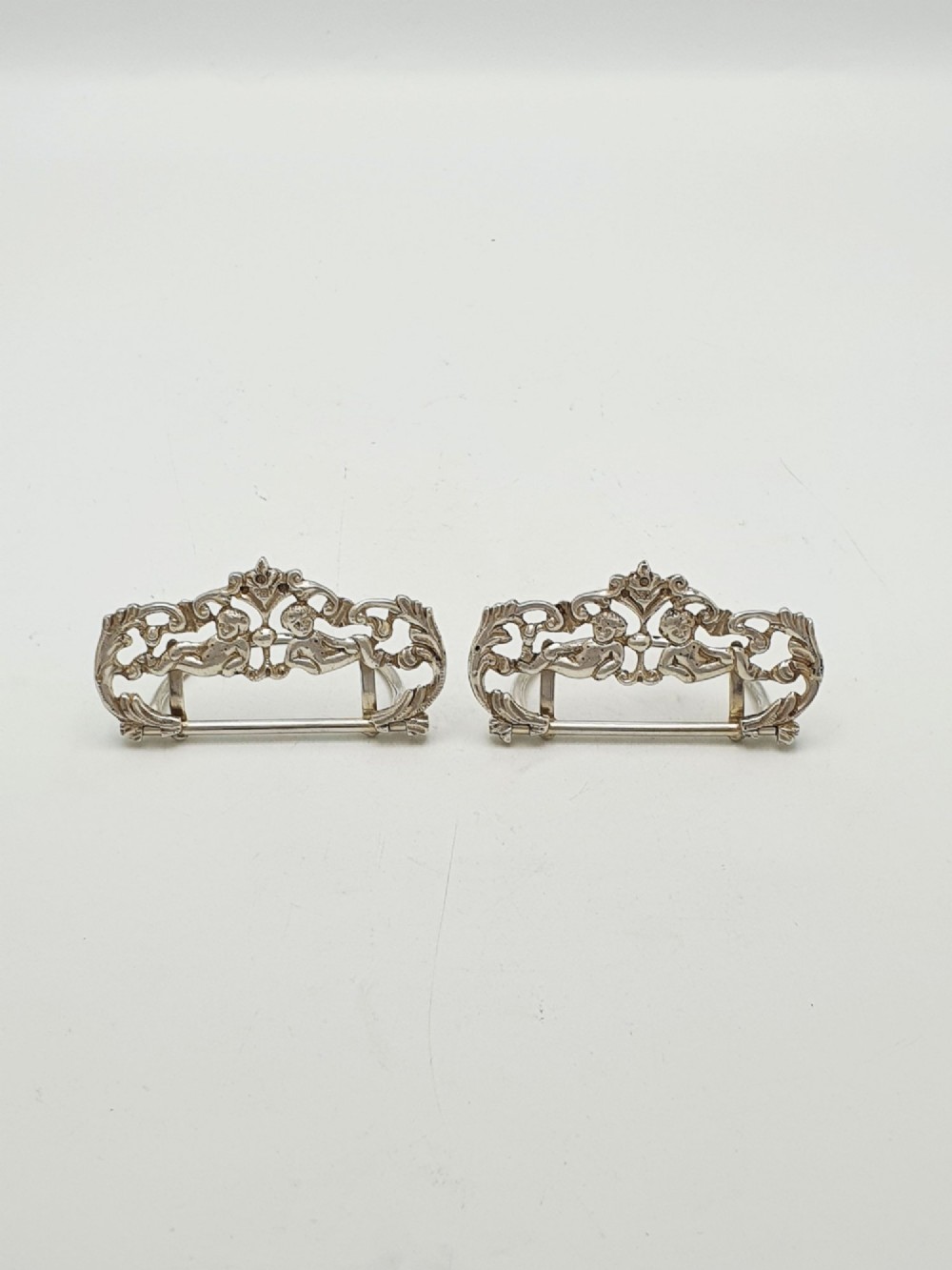 A pair of Victorian sterling silver place card holders featuring detailed cherubs framed by pierced scrolling foliage. View II