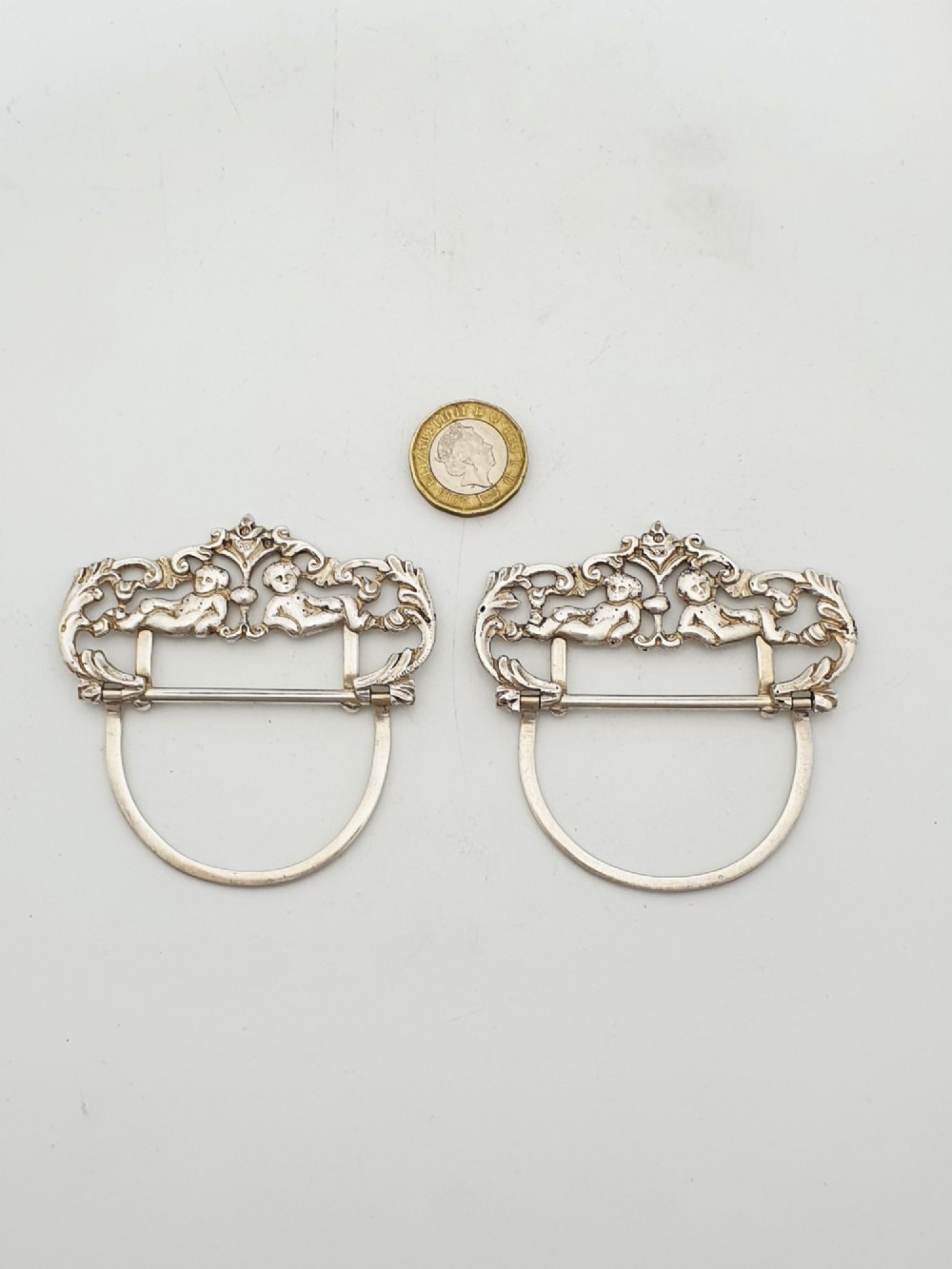 A pair of Victorian sterling silver place card holders featuring detailed cherubs framed by pierced scrolling foliage. View VII