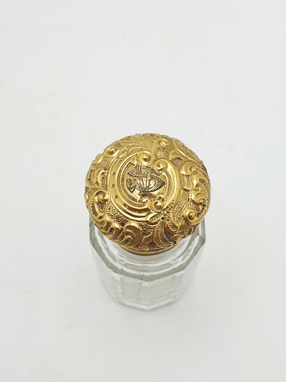 A clear faceted cut glass scent bottle featuring an embossed gilt sterling silver cap. View II
