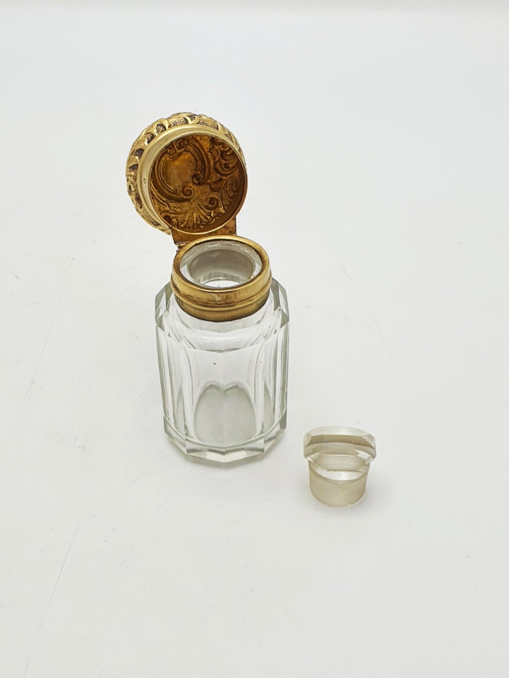 A clear faceted cut glass scent bottle featuring an embossed gilt sterling silver cap. View III