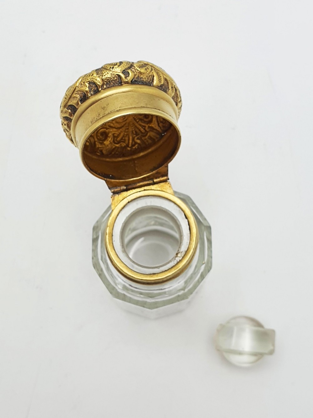 A clear faceted cut glass scent bottle featuring an embossed gilt sterling silver cap. View IV
