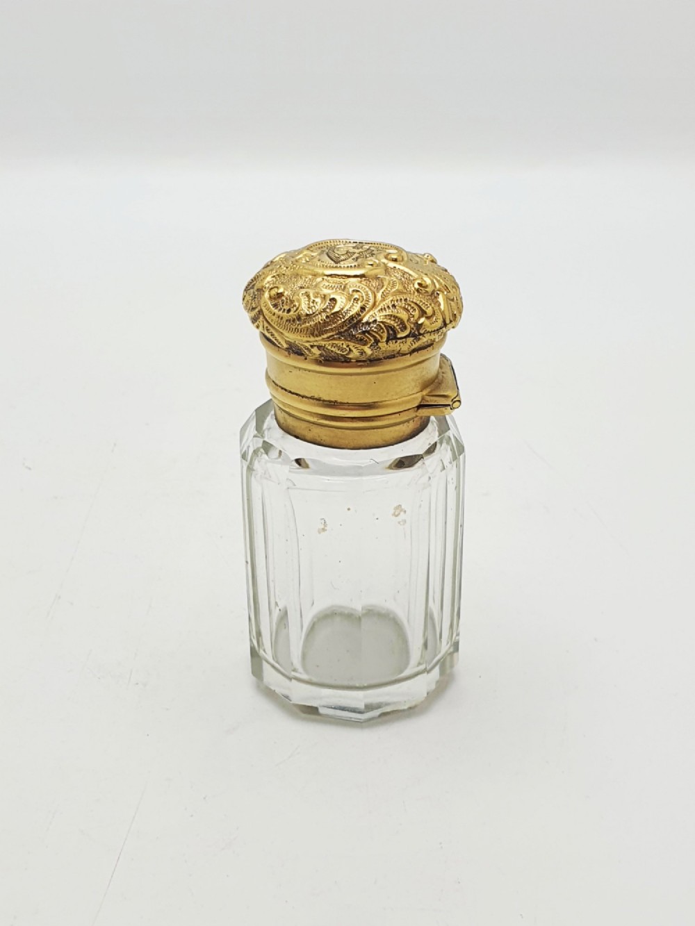 A clear faceted cut glass scent bottle featuring an embossed gilt sterling silver cap. View V