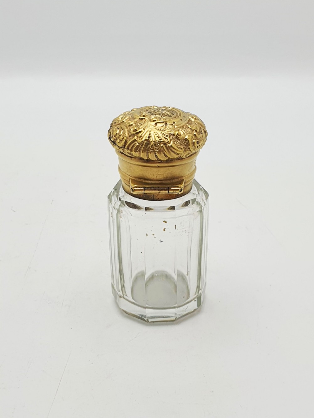 A clear faceted cut glass scent bottle featuring an embossed gilt sterling silver cap. View VI