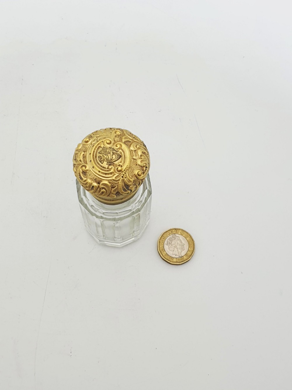 A clear faceted cut glass scent bottle featuring an embossed gilt sterling silver cap. View IX