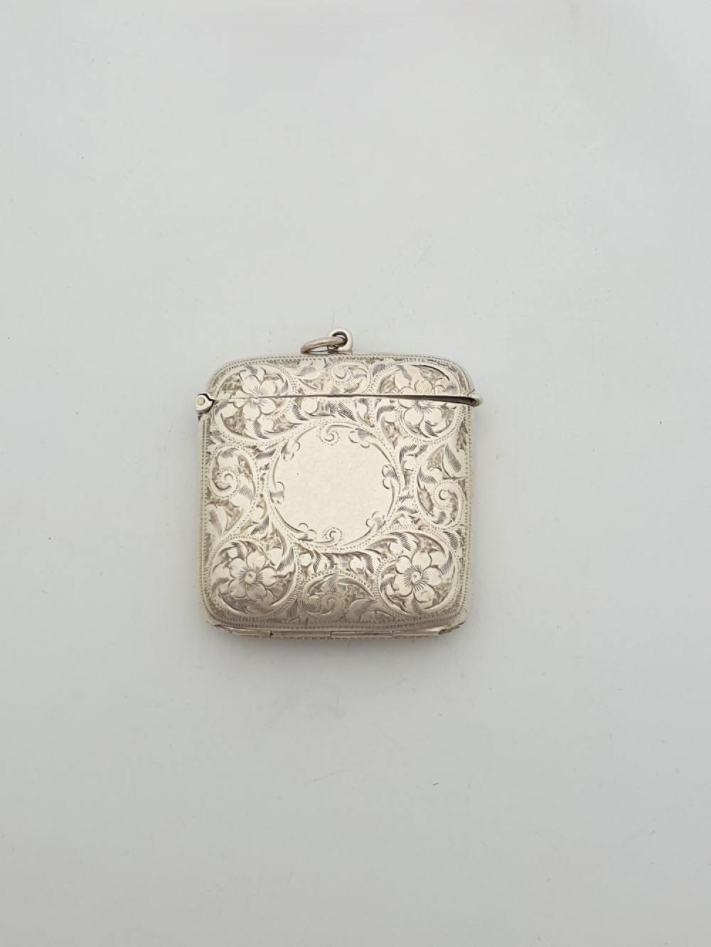 An open Edwardian sterling silver vesta case displaying an engraved hinged lid and two interior oval photo frame apertures. View II