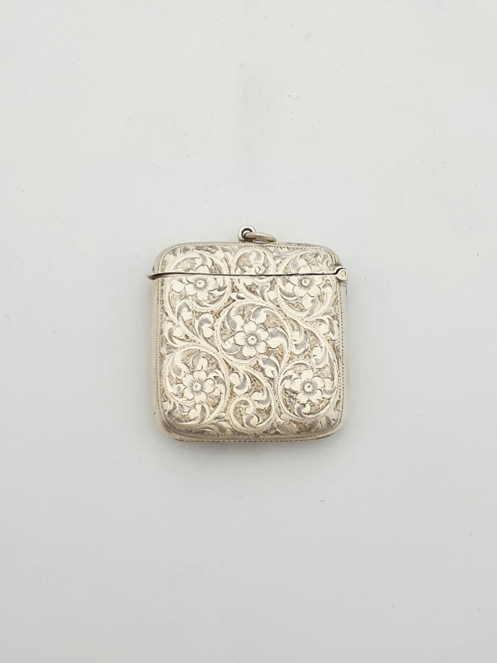 An open Edwardian sterling silver vesta case displaying an engraved hinged lid and two interior oval photo frame apertures. View III