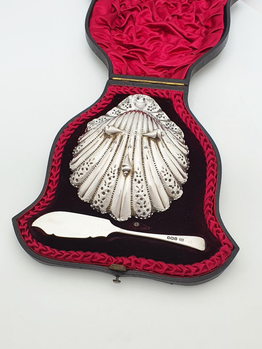 A Victorian sterling silver scallop shell butter dish and matching engraved spreader knife resting inside a fitted red and black velvet presentation case. View III