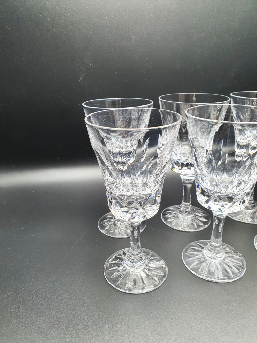 A set of eight clear cut glass wine glasses featuring faceted bowls and starburst pattern bases. View II