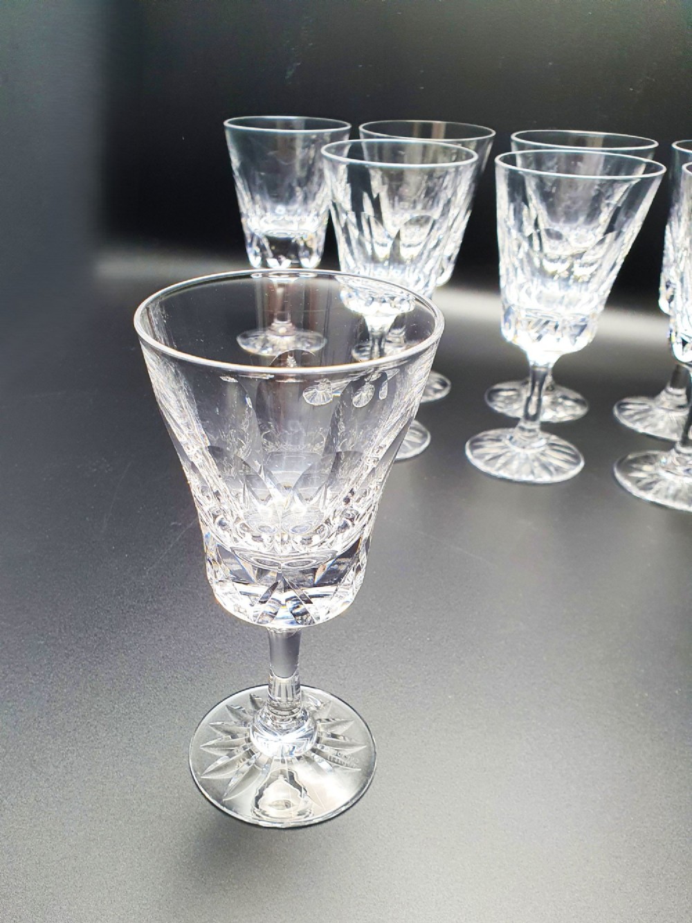 A set of eight clear cut glass wine glasses featuring faceted bowls and starburst pattern bases. View V