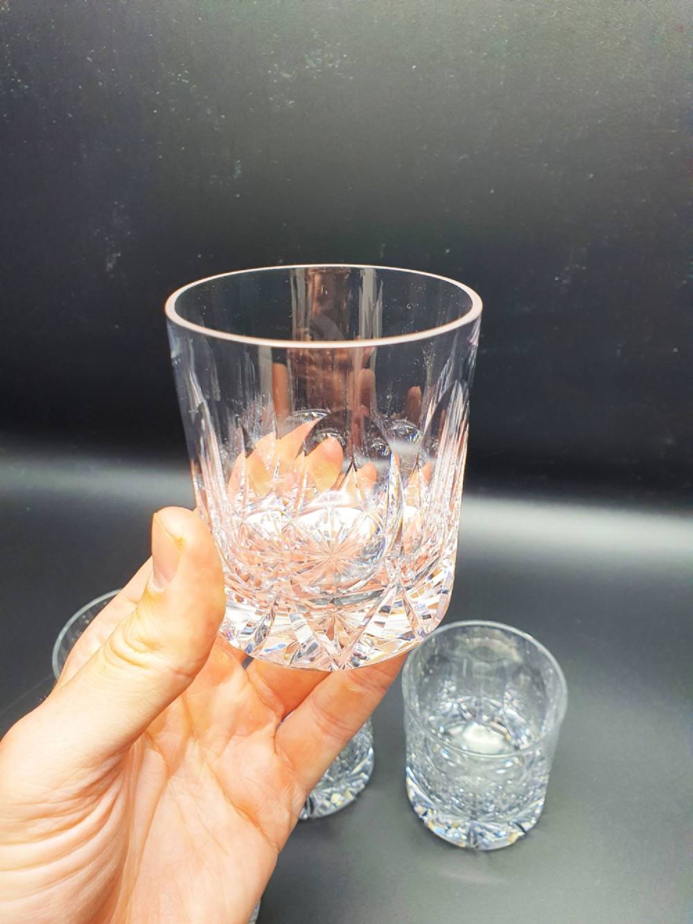 A set of five clear cut-glass tumblers featuring intricate geometric facet carvings around the lower half and base. View IV
