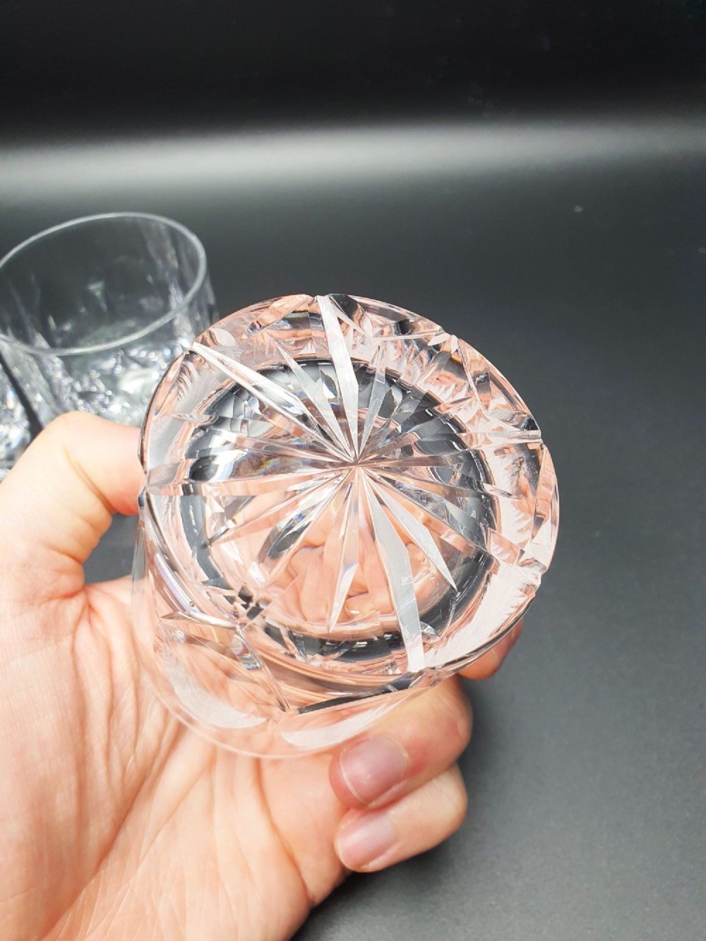A set of five clear cut-glass tumblers featuring intricate geometric facet carvings around the lower half and base. View V