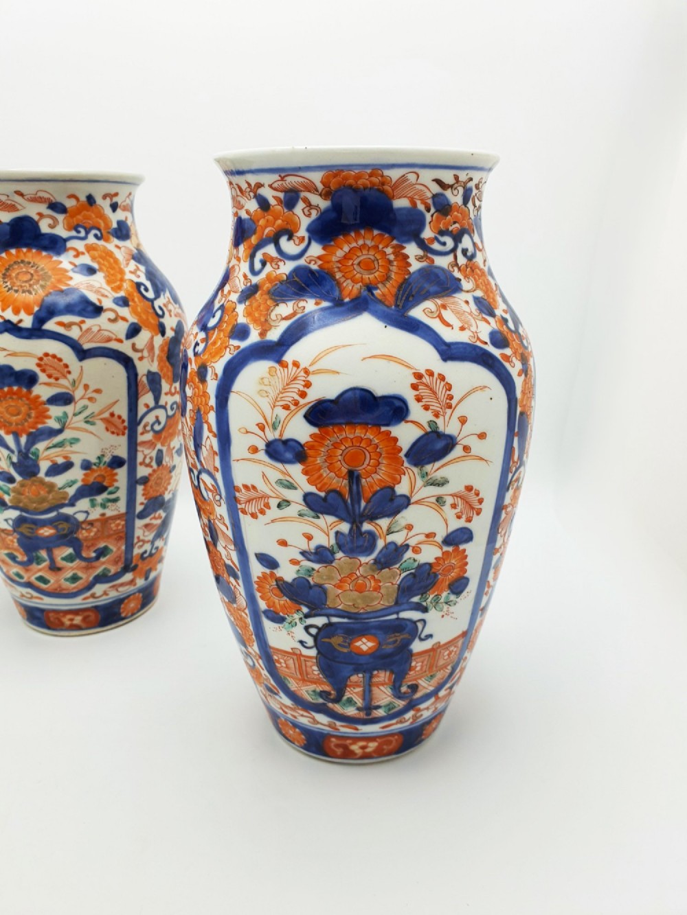 A pair of antique Japanese Imari porcelain vases decorated with cobalt blue and iron-red floral motifs within framed panels. View II
