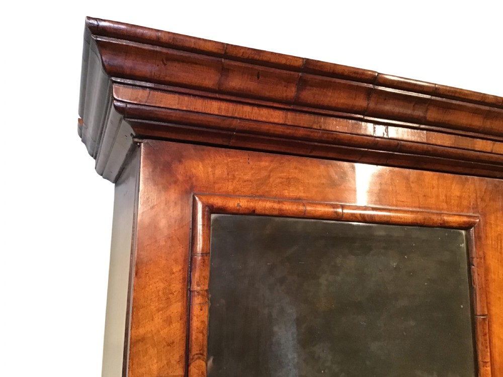 A two-part Georgian walnut bureau bookcase featuring a moulded top cabinet with two glazed doors above a fall-front desk with a green leather writing surface and a shaped lower drawer base. View V