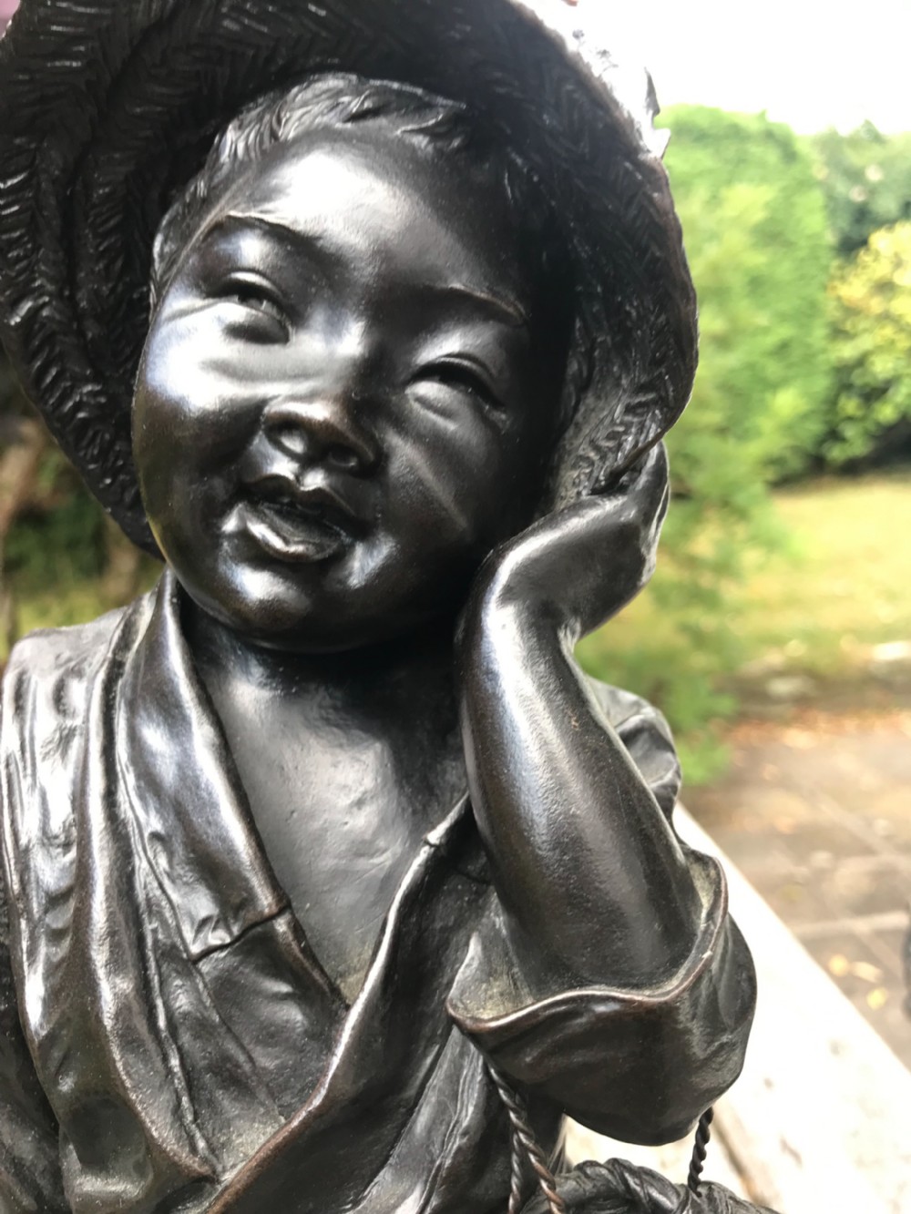 A dark patinated bronze okimono sculpture depicting a standing Japanese fisherman holding a tall rod with a basket slung over his shoulder. View III