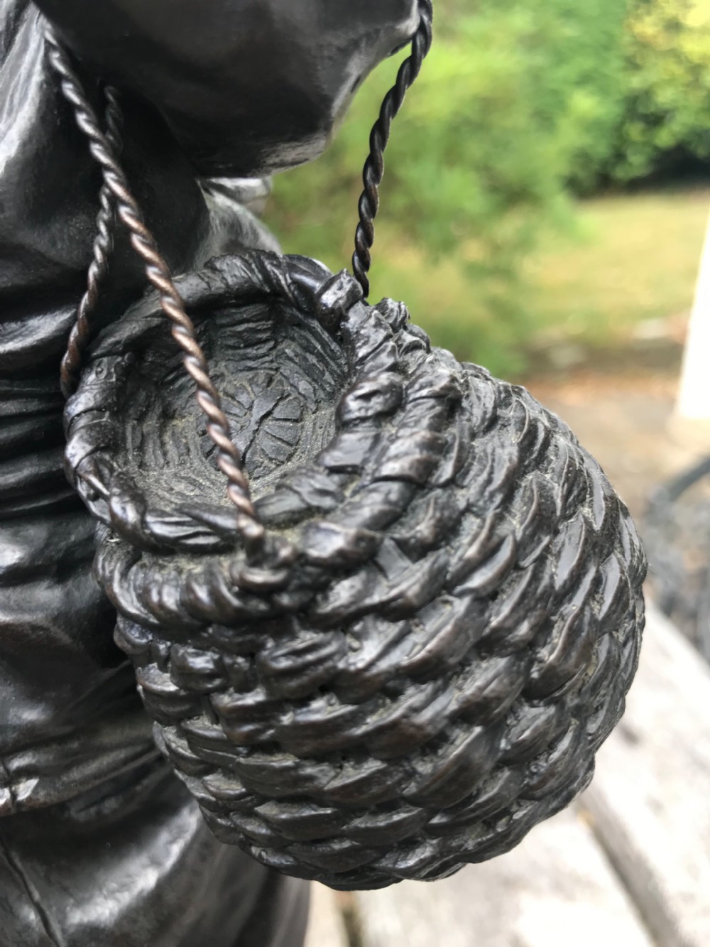 A dark patinated bronze okimono sculpture depicting a standing Japanese fisherman holding a tall rod with a basket slung over his shoulder. View IV