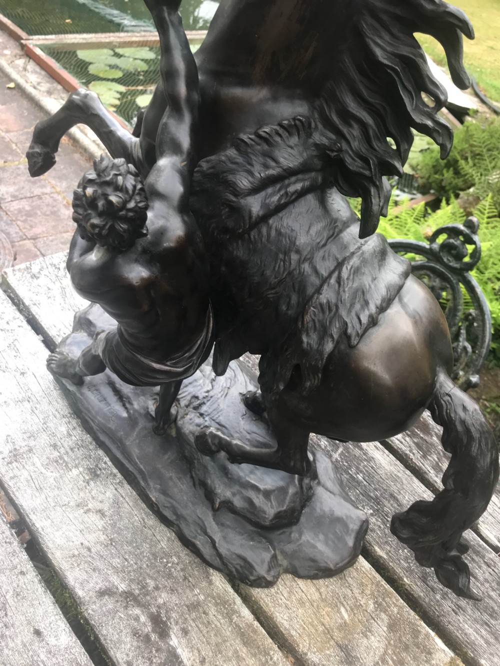 A dark patinated bronze sculpture depicting a muscular male groom attempting to restrain a rearing horse on a naturalistic base. View III