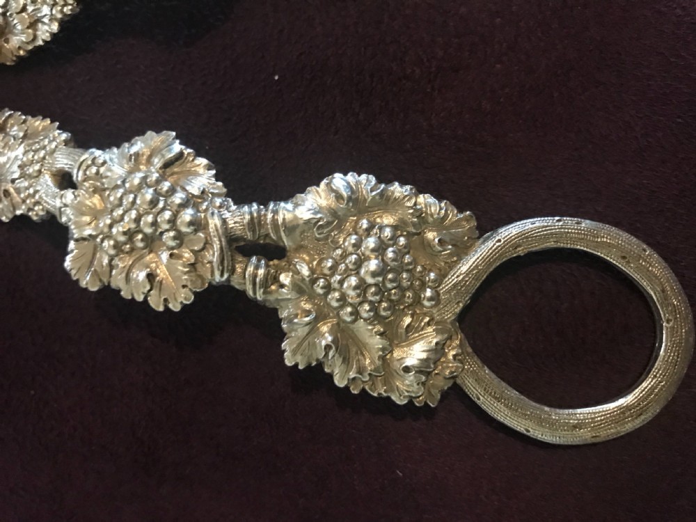 A pair of silver grape scissors featuring handles relief-moulded with grape clusters and vine leaves leading to round finger loops. View IV