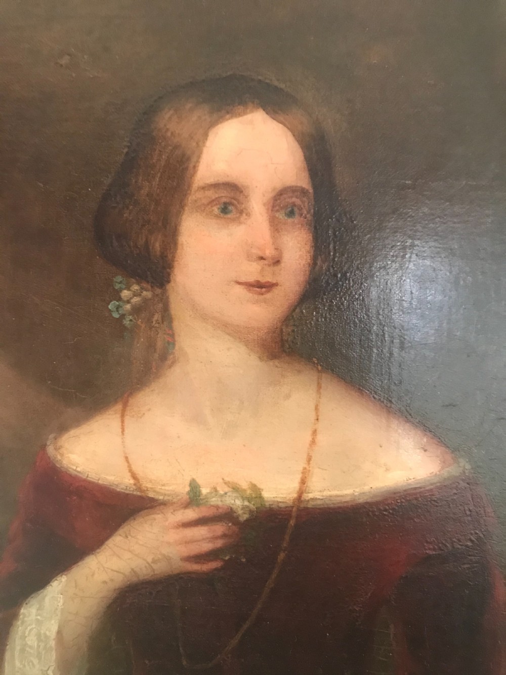 An antique oil painting on canvas depicting a woman in a deep red off-the-shoulder gown, enclosed within a wide gilded wooden frame. View III