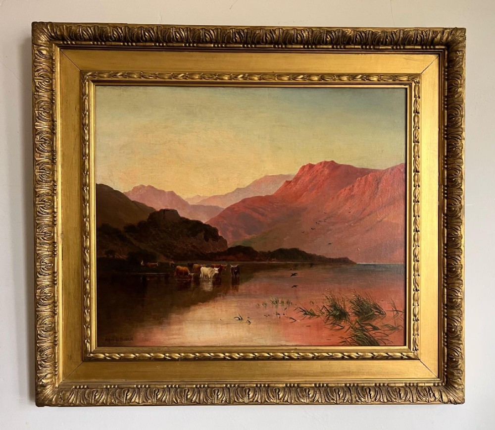 A Victorian oil painting depicting Highland cattle beside a serene loch under red mountain light, set in an ornate carved gilt frame.