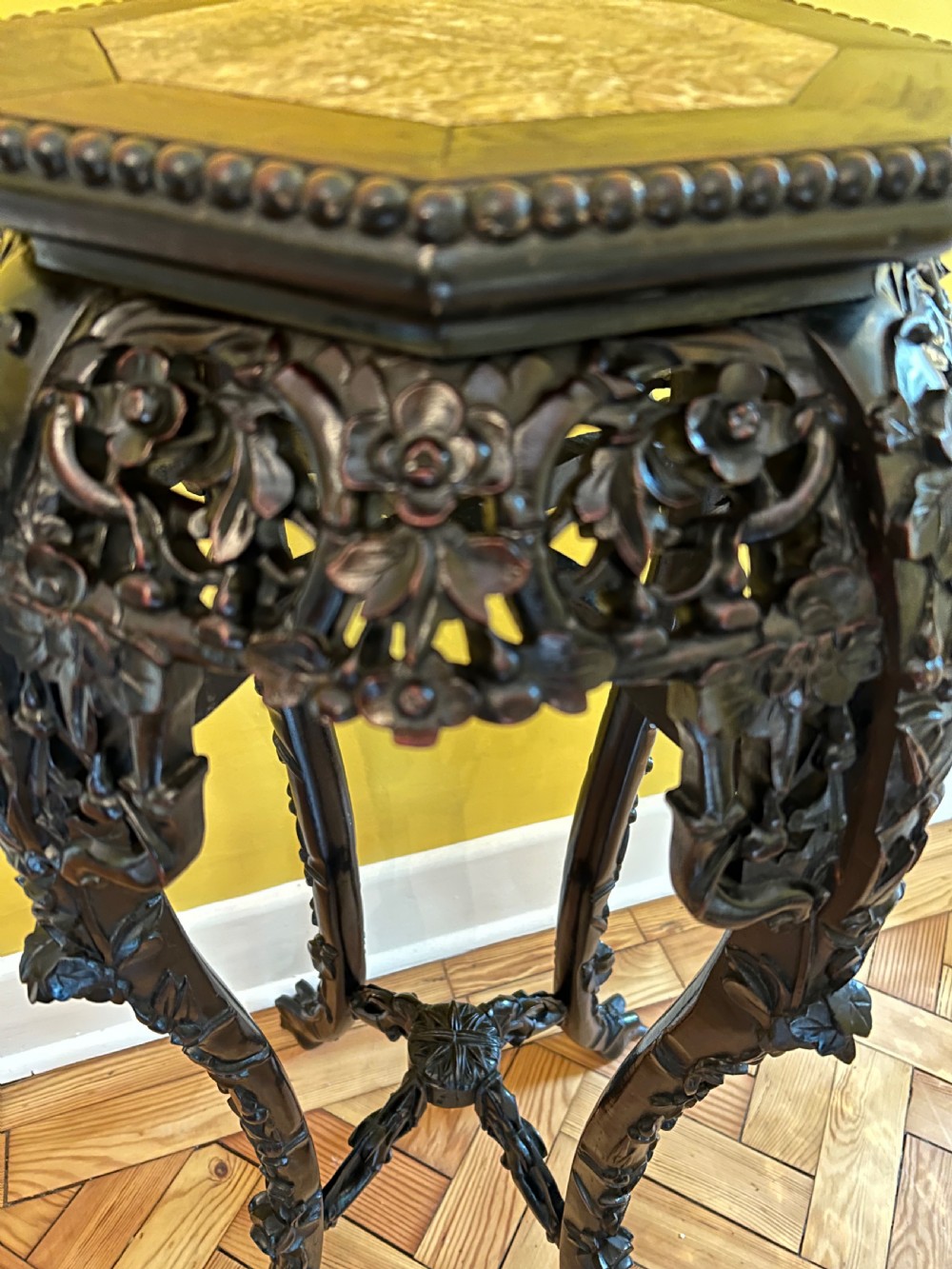 An intricately carved dark hardwood Chinese plant stand featuring an octagonal beaded top, openwork floral apron, cabriole legs, and a carved lower cross-stretcher. View V