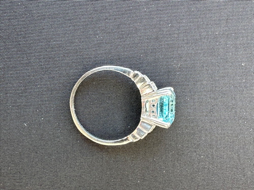 An Art Deco platinum ring featuring a central rectangular step-cut pale blue aquamarine flanked by stepped diamond-set shoulders. View II