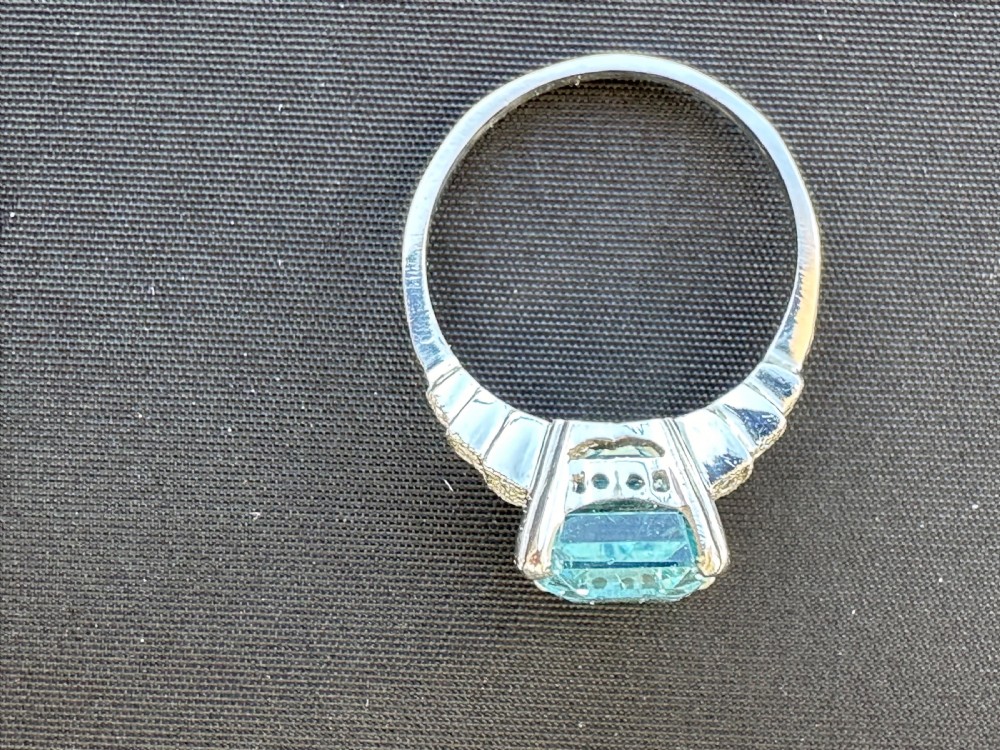 An Art Deco platinum ring featuring a central rectangular step-cut pale blue aquamarine flanked by stepped diamond-set shoulders. View III