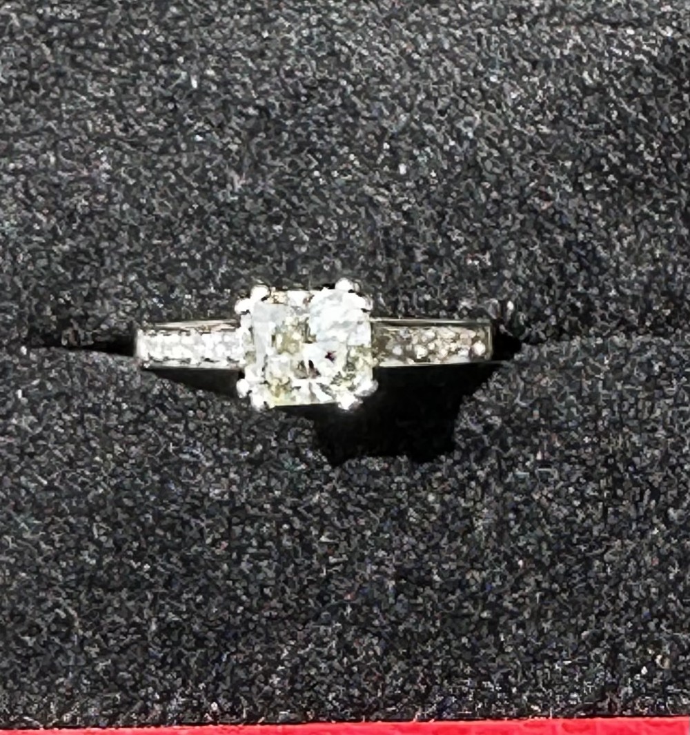 An 18ct gold solitaire ring featuring a central square-cut stone with accent stones set into the shoulders.