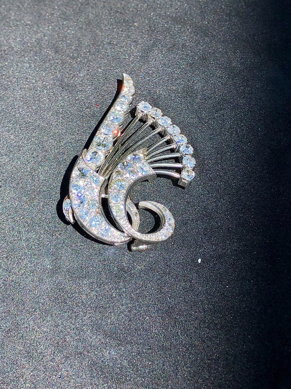 A late Art Deco platinum brooch styled as sweeping floral sprays and swirls encrusted with round brilliant cut diamonds.