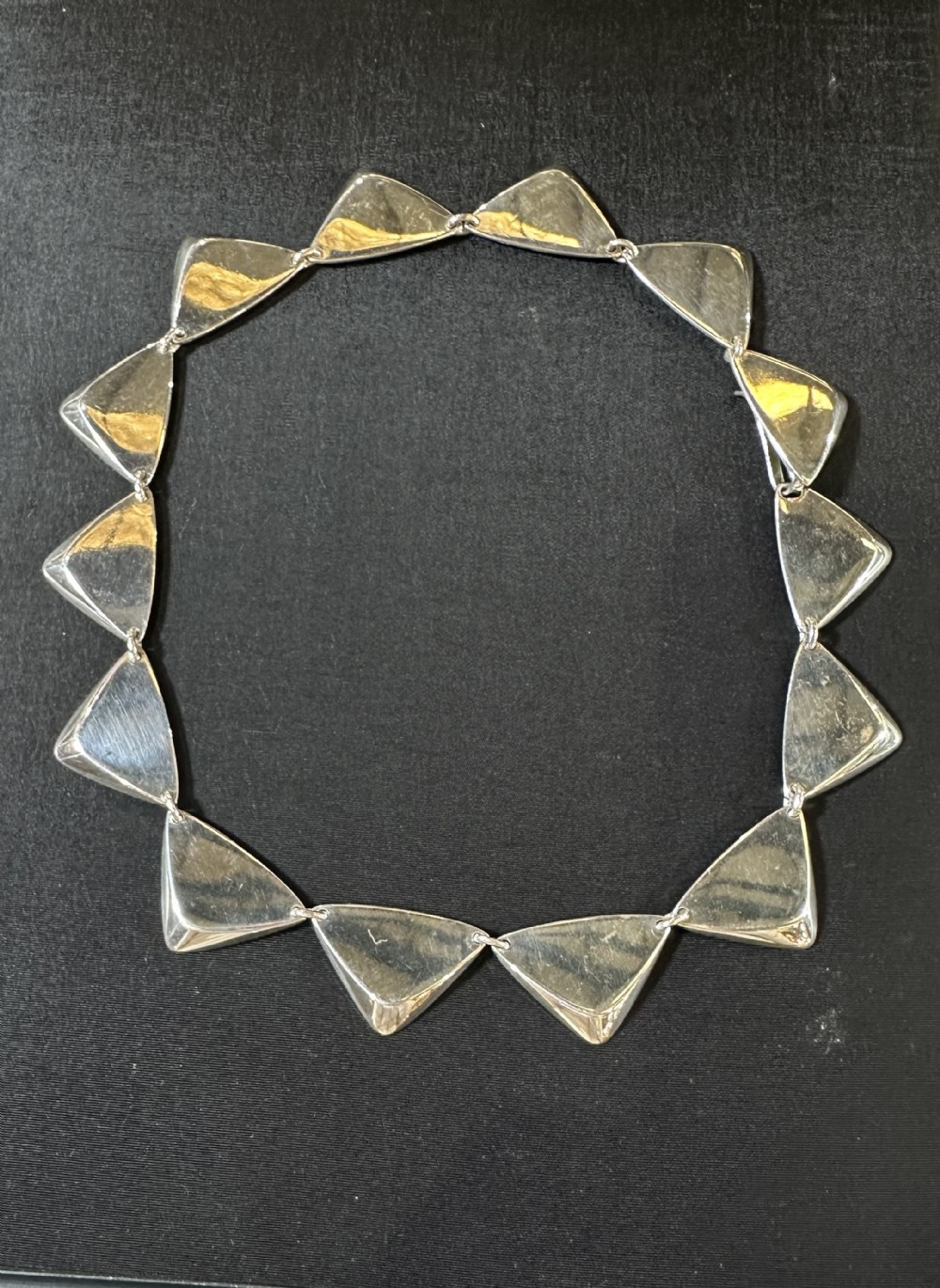 A sterling silver collar necklace featuring a series of articulated triangular peak-shaped links.