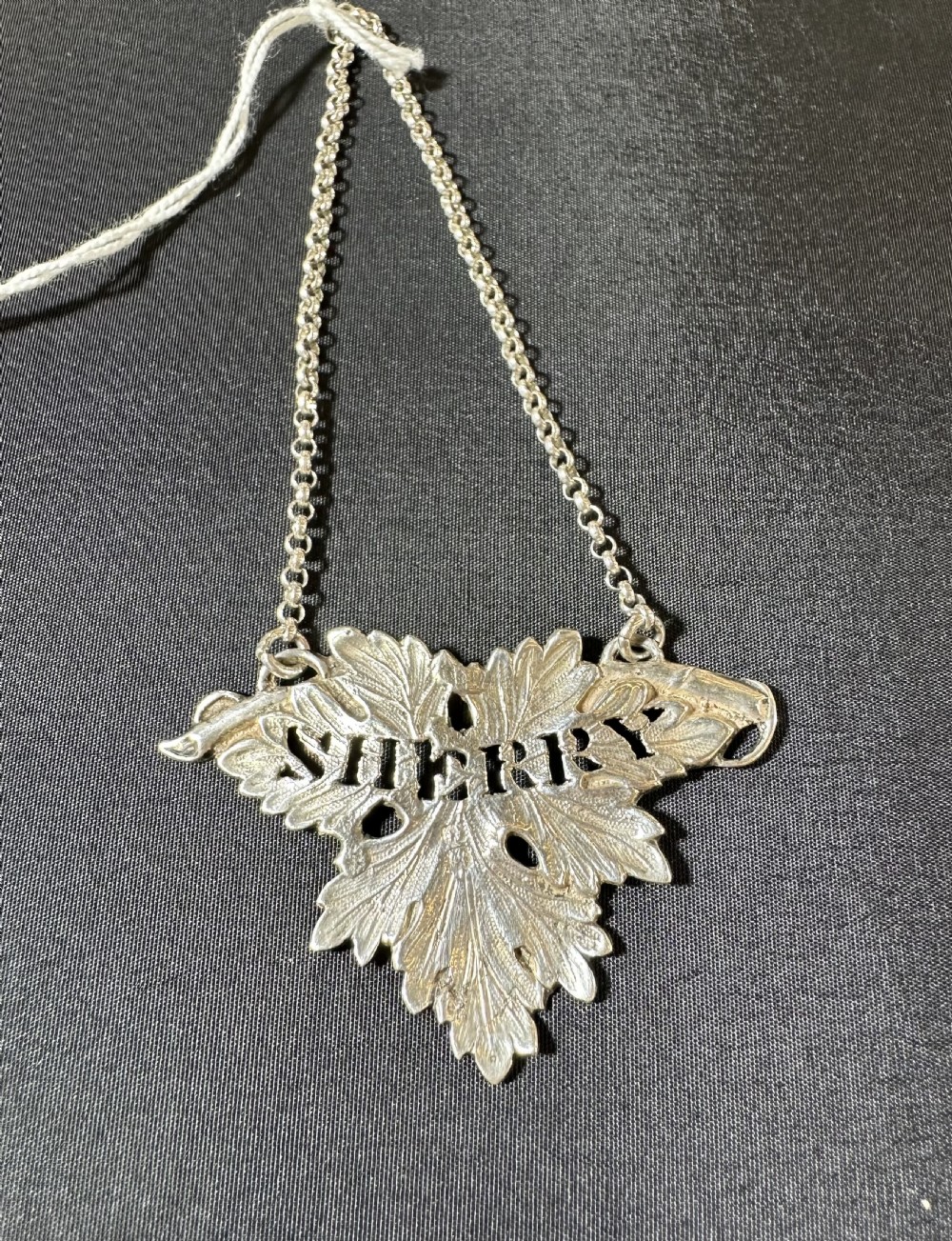 A Victorian sterling silver vine leaf decanter label for Sherry with pierced lettering and a fine silver chain.